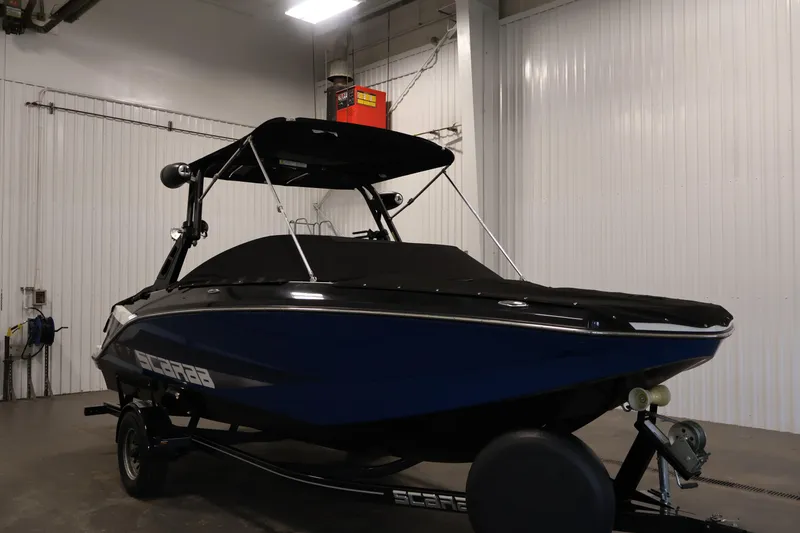 Slide: The Image of 2021 Scarab 215 ID boat in a garage, featuring a sleek black and blue design. - 48
