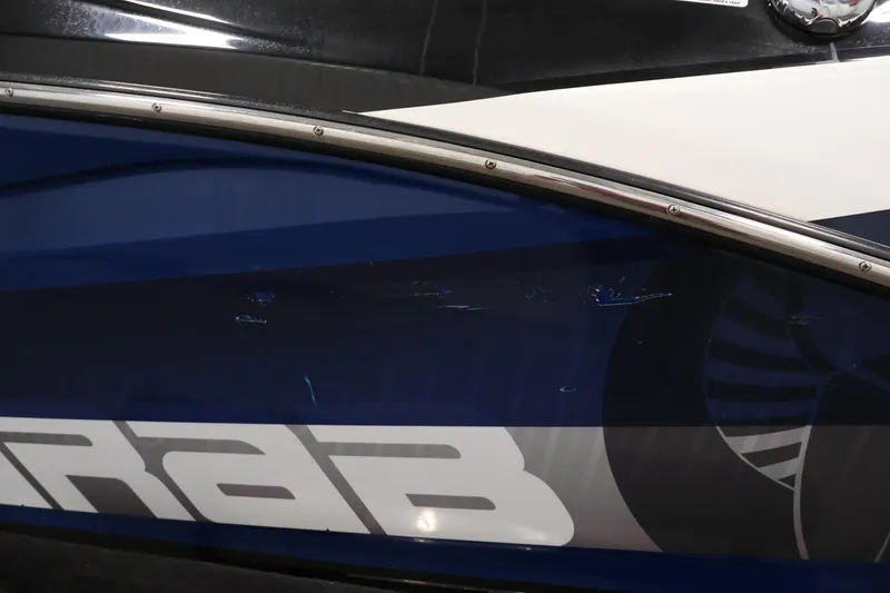 Slide: The Image of 2021 Scarab 215 ID boat side view with sleek blue and white design. - 49