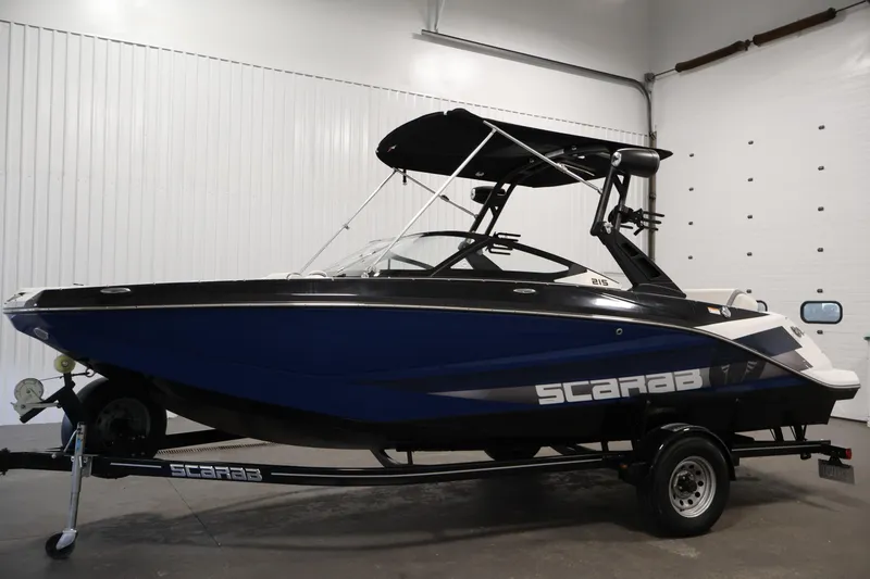 Slide: The Image of 2021 Scarab 215 ID boat in a showroom, featuring a sleek blue and black design. - 7