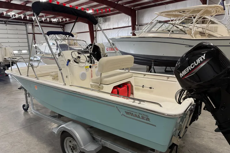 Slide: The Image of 2023 Boston Whaler 150 Montauk boat with Mercury engine in showroom. - 2