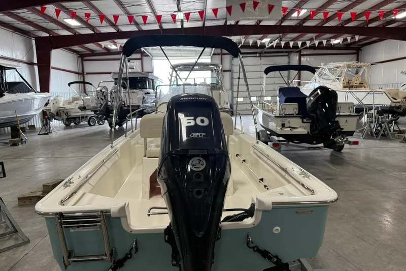 Slide: The Image of 2023 Boston Whaler 150 Montauk boat in showroom, featuring Mercury engine. - 4