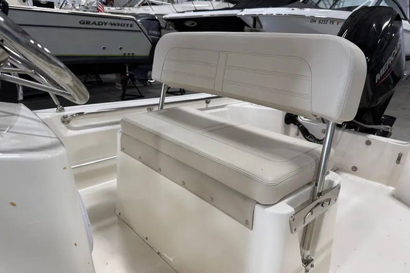 Slide: The Image of 2023 Boston Whaler 150 Montauk interior with white seating and steering wheel. - 6