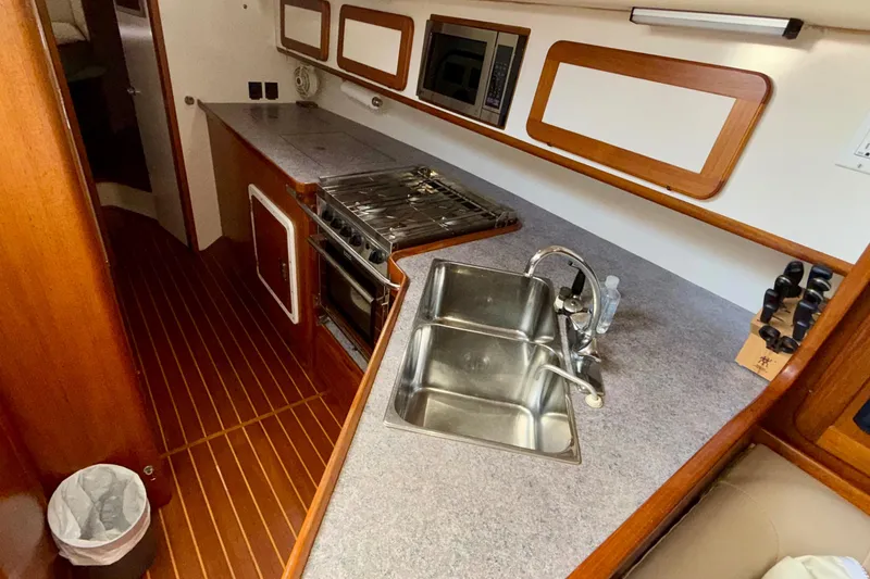 Slide: The Image of Galley kitchen in 2001 Caliber 47LRC yacht with stainless steel sink and wooden cabinetry. - 14