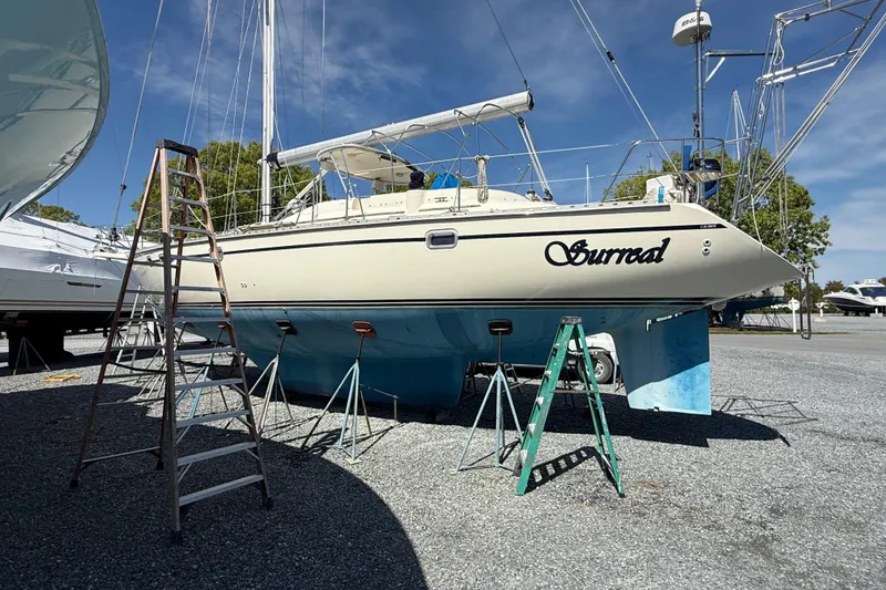 Slide: The Image of Sailboat Caliber 47LRC 2001 on stands, named "Surreal," in a boatyard with clear sky. - 3
