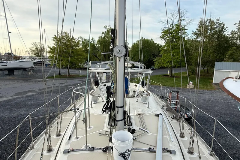 Slide: The Image of Deck view of a 2001 Caliber 47LRC sailboat on land, surrounded by trees and other boats. - 6