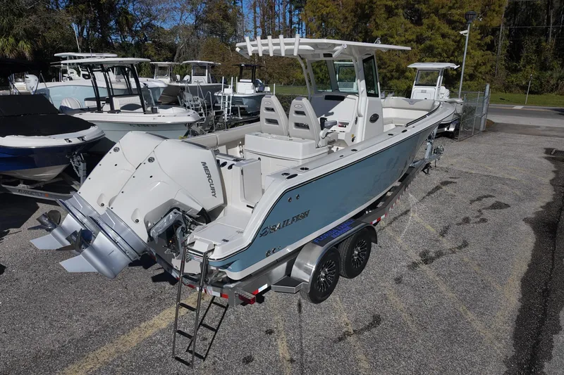 Slide: The Image of 2026 Sailfish 272 CC boat with dual Mercury engines on a trailer in a marina. - 2