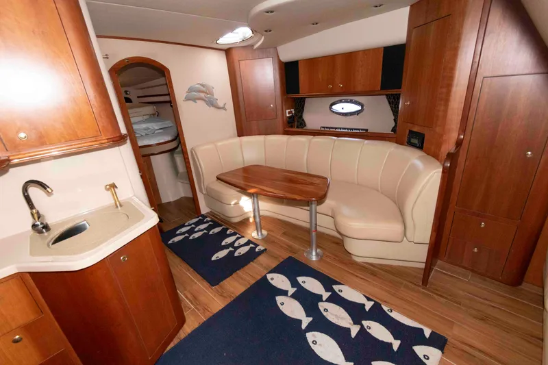 Slide: The Image of 2001 Cruisers Yachts 3672 Express interior with wood cabinetry, curved seating, and nautical decor. - 11