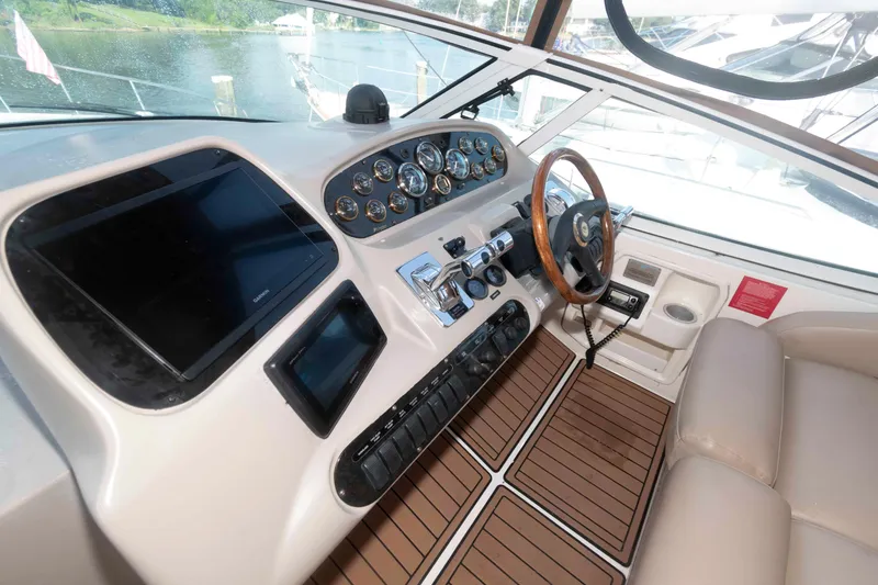 Slide: The Image of 2001 Cruisers Yachts 3672 Express helm with wood accents and modern controls. - 8