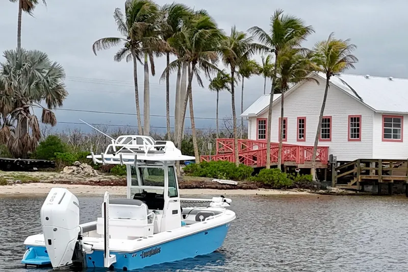 Slide: The Image of 2024 Everglades 253 Center Console boat near tropical shoreline with palm trees and a house. - 15