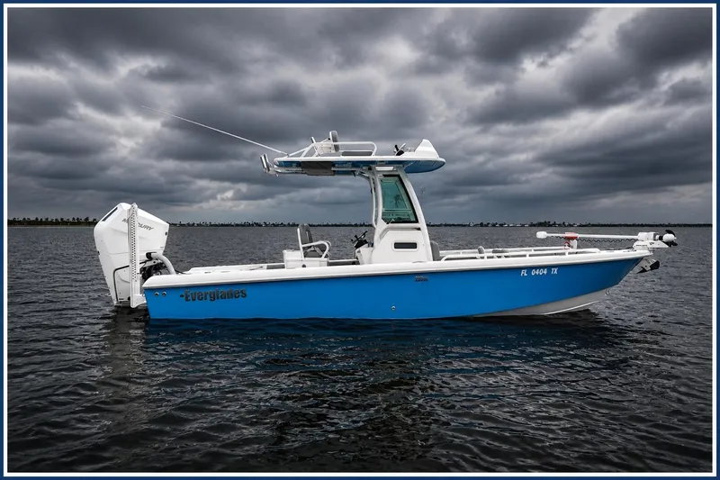 Slide: The Image of 2024 Everglades 253 Center Console boat on water under cloudy sky. - 2