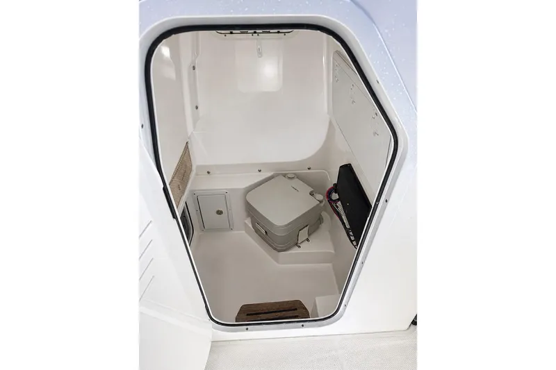 Slide: The Image of 2024 Everglades 253 Center Console interior cabin with compact toilet and storage. - 35