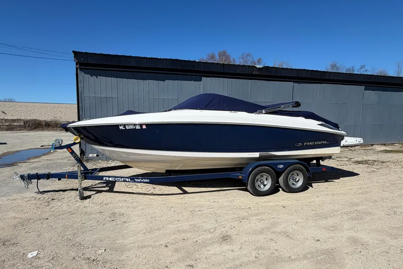 The Image of 2019 Regal 2300 Bowrider boat on trailer, parked outdoors under clear blue sky. - 0