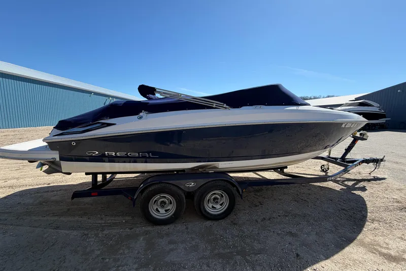 Slide: The Image of 2019 Regal 2300 Bowrider boat on trailer under clear blue sky. - 3