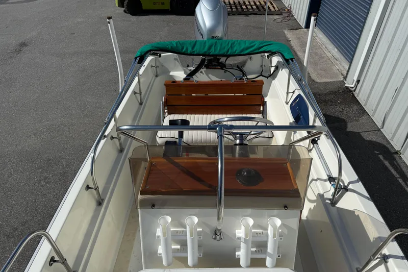Slide: The Image of 1978 Boston Whaler 17 Montauk boat interior with green canopy and wooden console. - 11