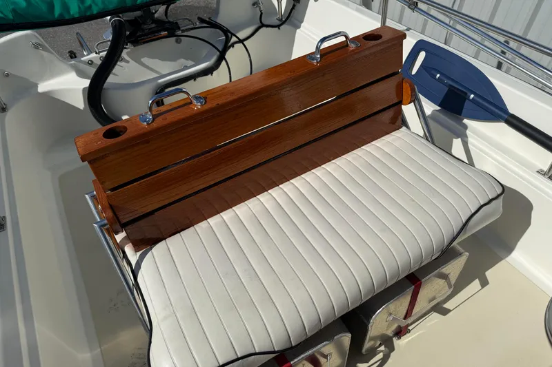 Slide: The Image of 1978 Boston Whaler 17 Montauk boat seat with wooden backrest and white cushion. - 8