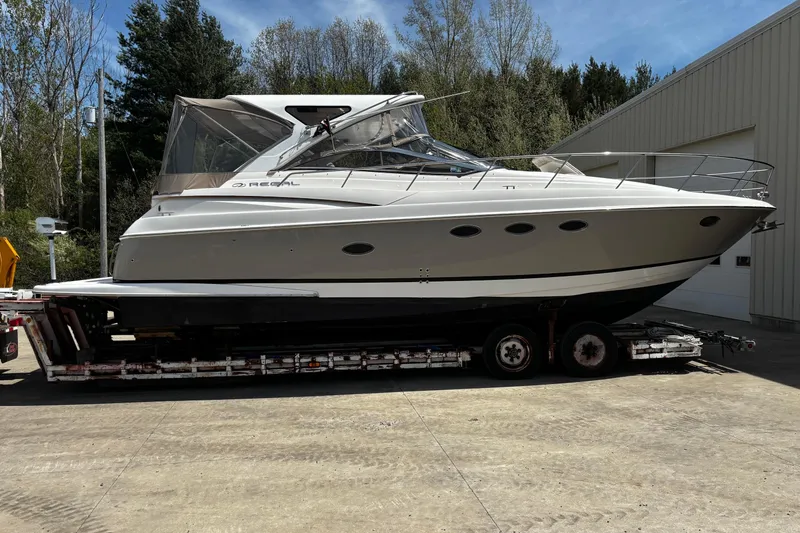 The Image of 2006 Regal Commodore 3860 yacht on trailer, parked outdoors near trees and building. - 0
