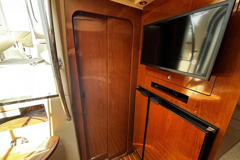 Slide: The Image of 2006 Regal Commodore 3860 interior with TV, wooden cabinetry, and refrigerator. - 14