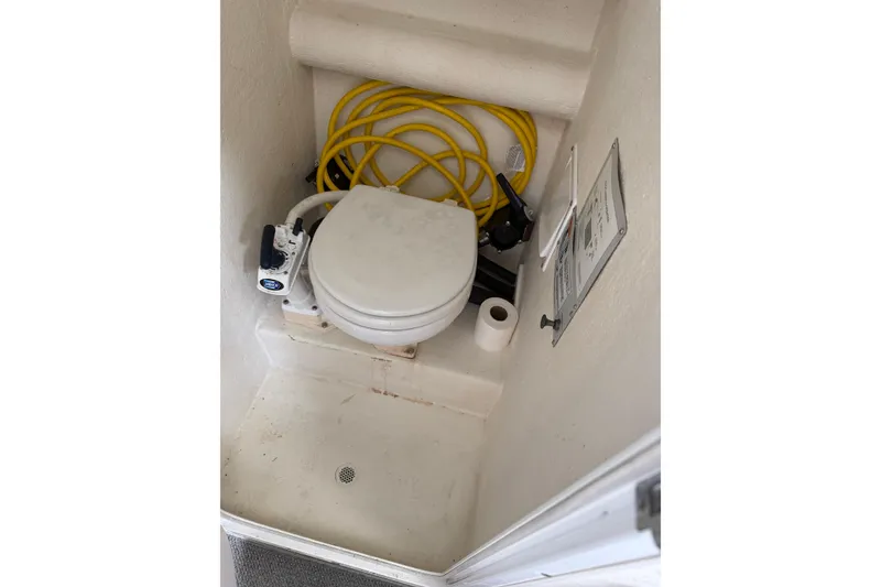 Slide: The Image of 2005 SeaSport Explorer 2400 boat toilet area with yellow hose and toilet paper. - 15