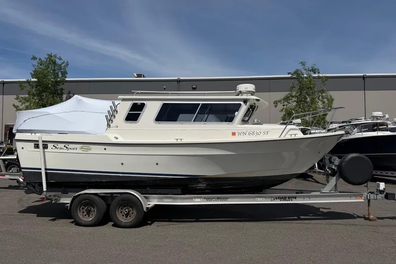 Slide: The Image of 2005 SeaSport Explorer 2400 boat on trailer, parked outdoors under clear sky. - 3