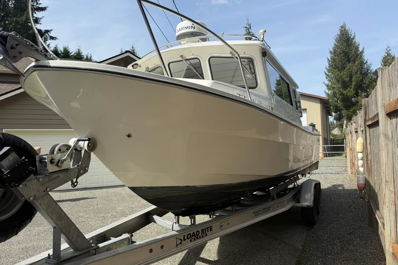 Slide: The Image of 2005 SeaSport Explorer 2400 boat on trailer in driveway, surrounded by trees and houses. - 4