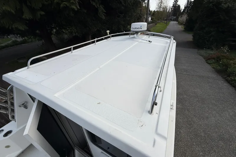 Slide: The Image of 2005 SeaSport Explorer 2400 boat roof with Garmin radar, parked near trees. - 7