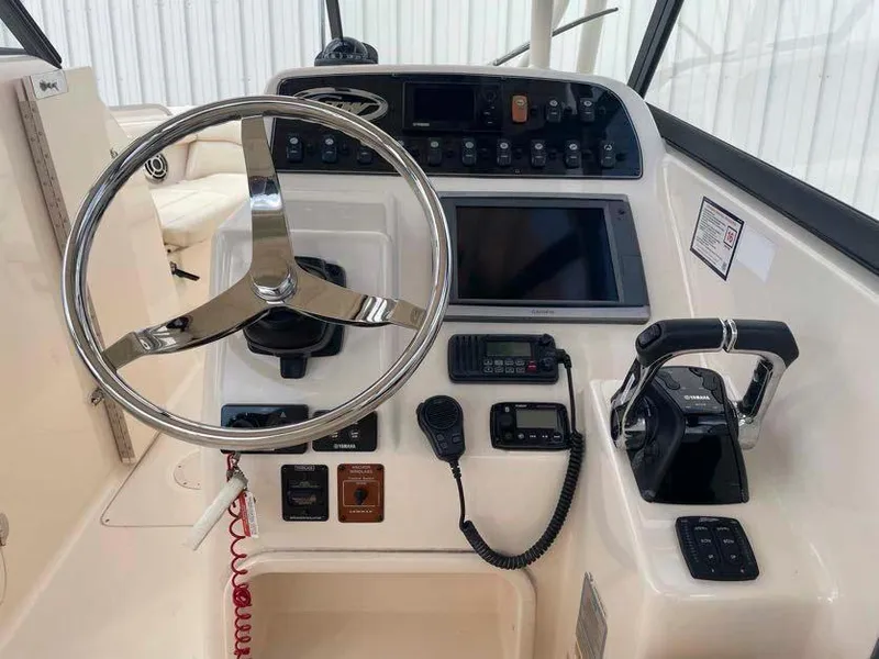 Slide: The Image of 2015 Grady-White Freedom 275 boat dashboard with steering wheel and controls. - 11