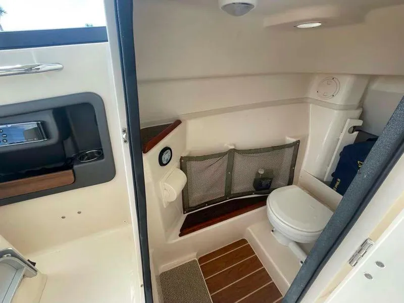 Slide: The Image of 2015 Grady-White Freedom 275 boat interior with compact bathroom and wooden flooring. - 22