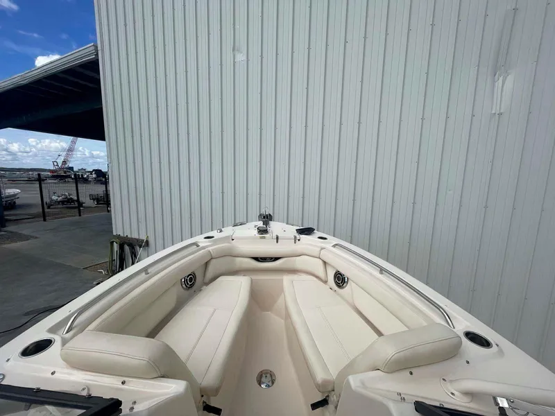 Slide: The Image of 2015 Grady-White Freedom 275 boat interior with white seating, docked near a metal building. - 9
