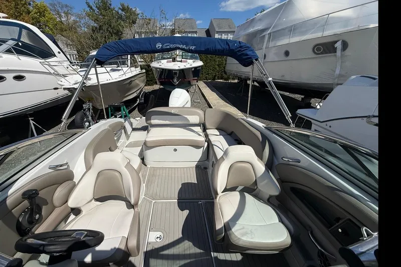 Slide: The Image of 2019 Crownline Eclipse E235 XS boat interior with seating and canopy, docked among other boats. - 16