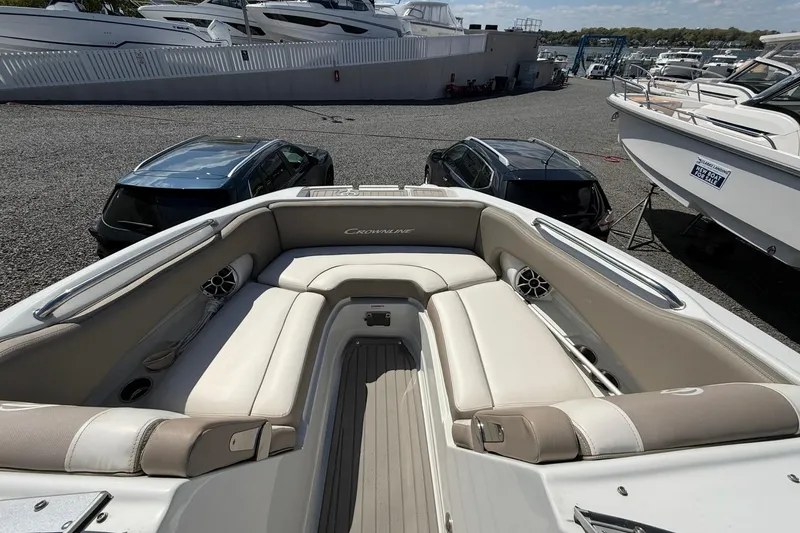 Slide: The Image of 2019 Crownline Eclipse E235 XS boat interior with beige seating, docked near other boats. - 18