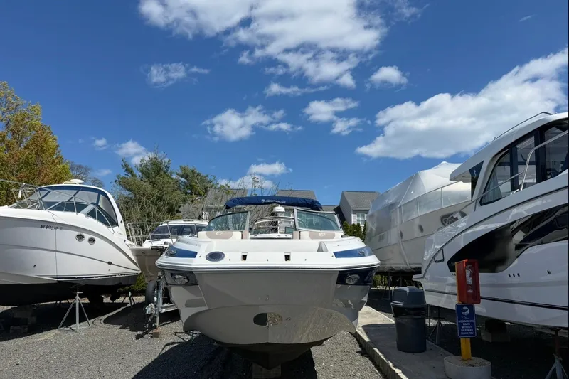 Slide: The Image of 2019 Crownline Eclipse E235 XS boat in storage, surrounded by other vessels under a clear blue sky. - 3