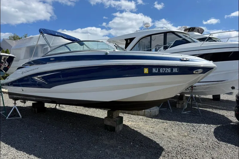 Slide: The Image of 2019 Crownline Eclipse E235 XS boat on display, blue and white exterior, parked on gravel. - 4