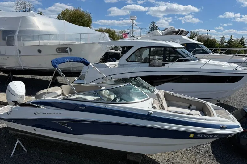 Slide: The Image of 2019 Crownline Eclipse E235 XS boat in a marina, surrounded by other vessels. - 8