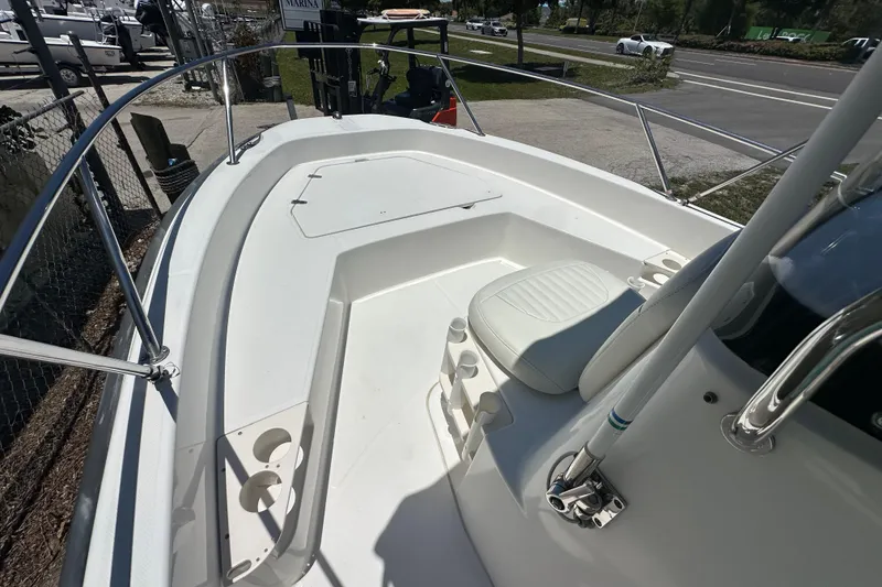 Slide: The Image of 2007 Boston Whaler 200 Dauntless boat deck with seating and railing, parked near a marina. - 12