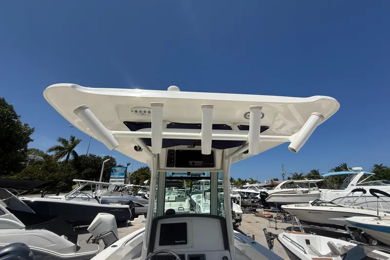 Slide: The Image of 2014 Boston Whaler 250 Outrage boat with T-top and rod holders under clear blue sky. - 16