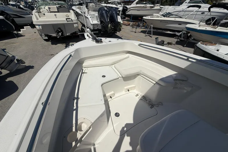 Slide: The Image of 2014 Boston Whaler 250 Outrage boat interior with seating and storage, docked among other boats. - 18