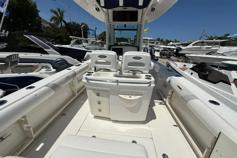 Slide: The Image of 2014 Boston Whaler 250 Outrage boat interior with seating and storage, docked under clear skies. - 3