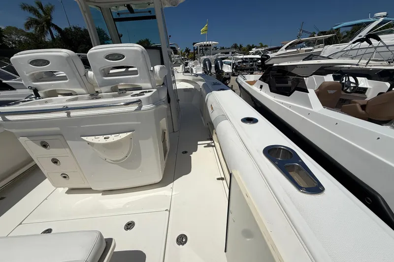Slide: The Image of 2014 Boston Whaler 250 Outrage boat interior with seating and storage, docked alongside other boats. - 4