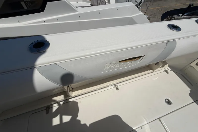Slide: The Image of 2014 Boston Whaler 250 Outrage boat interior with rod holders and storage compartment. - 7