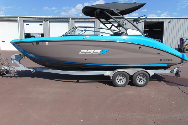 The Image of 2022 Yamaha Boats 255XD on trailer, blue and gray design, parked outdoors. - 1