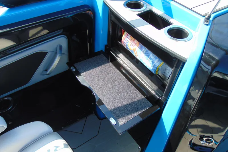 Slide: The Image of 2022 Yamaha Boats 255XD interior storage compartment with cup holders and open shelf. - 15