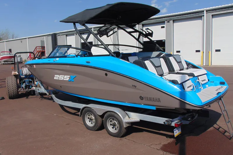 Slide: The Image of 2022 Yamaha Boats 255XD in blue and gray on a trailer, parked outdoors. - 3