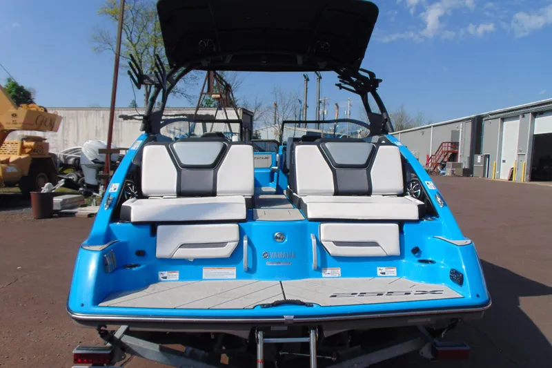 Slide: The Image of 2022 Yamaha Boats 255XD, blue exterior, rear view with seating, parked outdoors. - 5