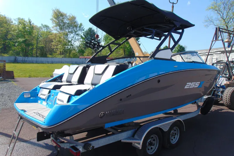 Slide: The Image of 2022 Yamaha Boats 255XD in blue and gray on a trailer, parked outdoors. - 6