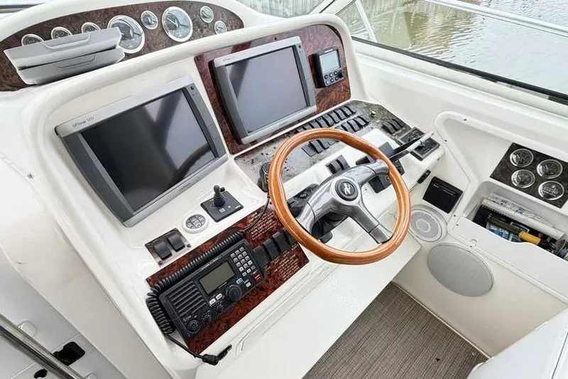 Slide: The Image of 1998 Sea Ray 370 Express Cruiser helm with dual screens and wooden steering wheel. - 24
