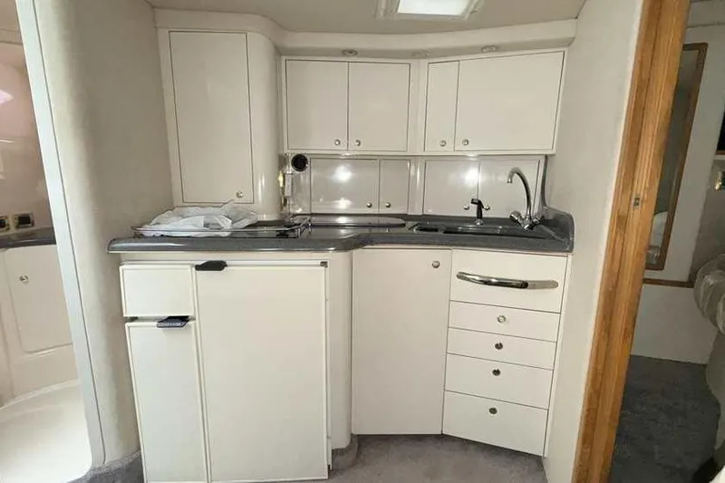 Slide: The Image of 1998 Sea Ray 370 Express Cruiser kitchen with white cabinets and compact design. - 33