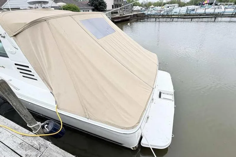Slide: The Image of 1998 Sea Ray 370 Express Cruiser docked with beige cover, rear view. - 6