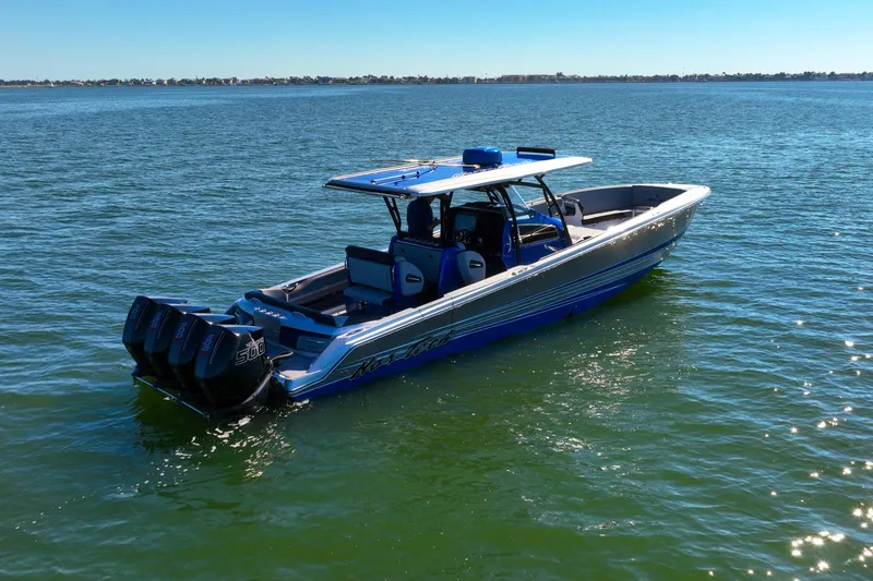 Slide: The Image of 2025 Nor-Tech 390 Sport Center Console boat on open water, featuring triple outboard engines. - 2