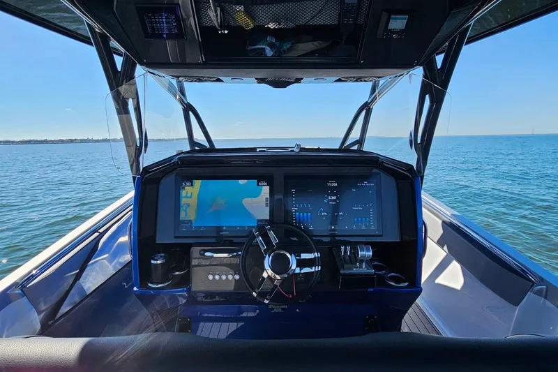 Slide: The Image of 2025 Nor-Tech 390 Sport Center Console dashboard with navigation screens on open water. - 24