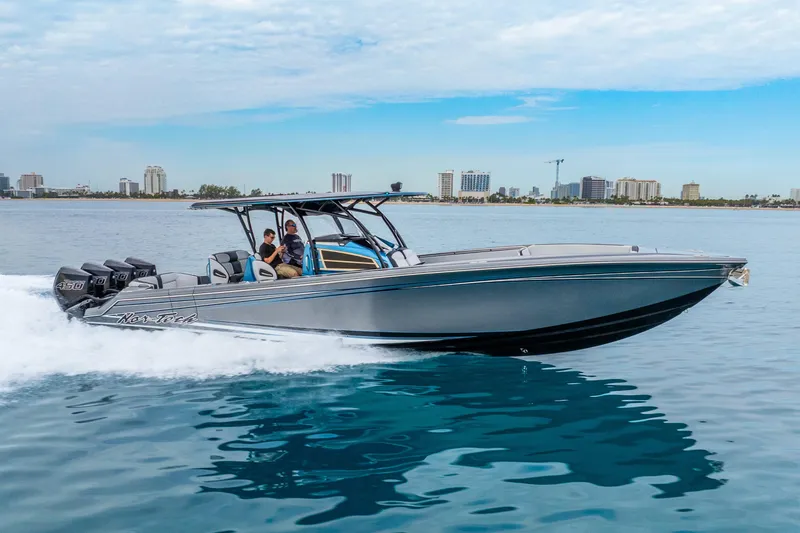Slide: The Image of 2024 Nor-Tech 390 Sport Center Console cruising on calm waters near a city skyline. - 13
